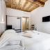 Rome Frattina 27 in Rome: bright bedroom with white bed, exposed wood ceiling, wall TV and built-in shelf
