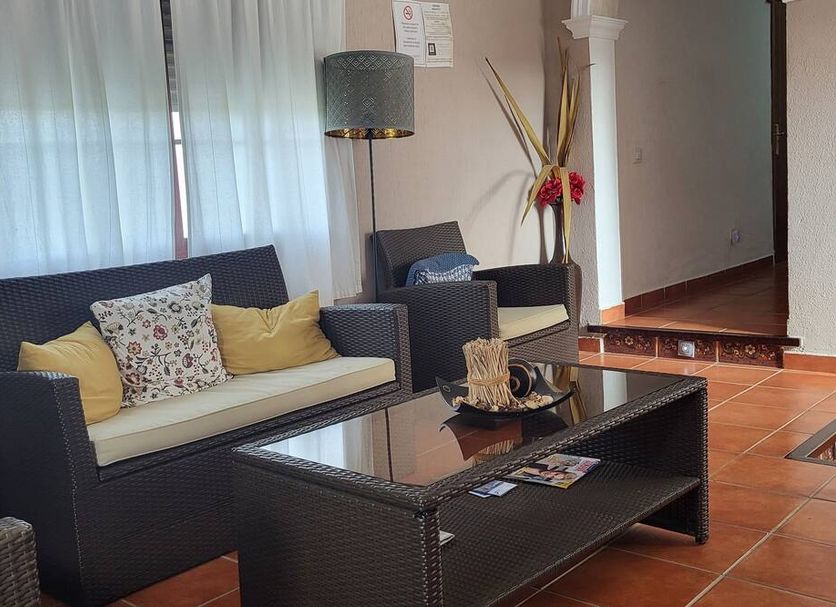Hostal Rural La Plata Parking Incluido lounge with wicker sofa, armchair, coffee table and floor lamp in Arcos de la Frontera