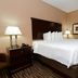 Cobblestone Inn & Suites - Denison guest room with king bed, bedside lamps and wood furnishings