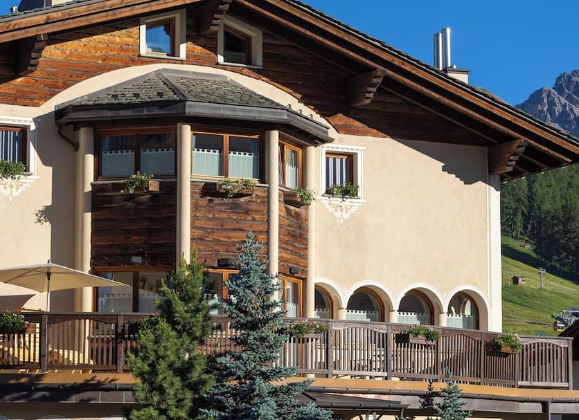Hotel Flora in Livigno with wooden chalet exterior, mountain backdrop and terrace