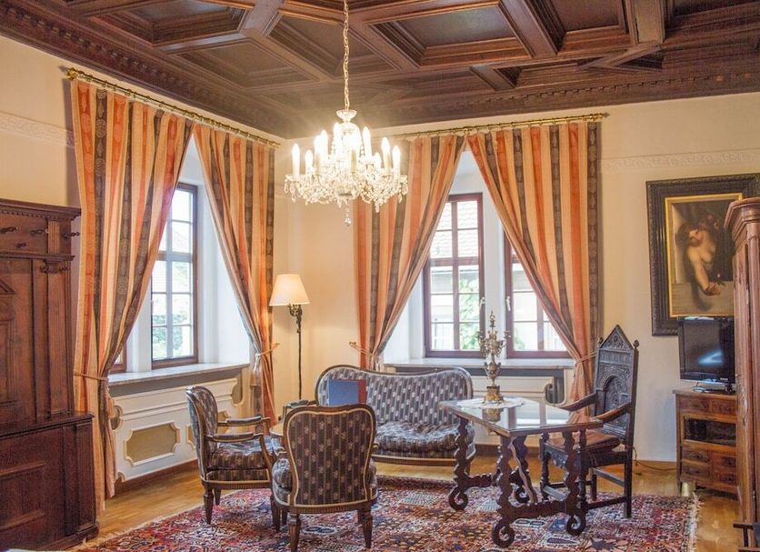 Hotel Vier Jahreszeiten in Volkach: elegant lounge with chandelier, striped drapes, and antique furniture