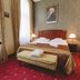 Mozart Hotel Szeged guest room with double bed, bench, bedside lamps, and patterned wallpaper