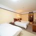 Hubin Bubugao Hotel in Qingyuan guest room with two beds, desk, TV and warm lighting