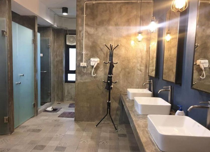Silom Space Hostel Bangkok bathroom with dual sinks, mirrors, showers and towel rack