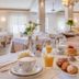 Hotel Massimo Cecina breakfast table with coffee, orange juice, pastries and pancakes in a bright dining room