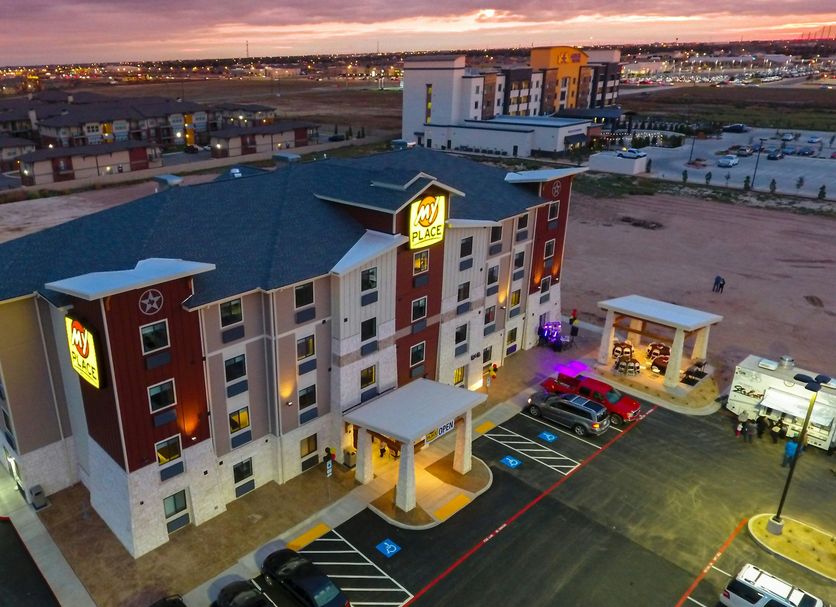 My Place Hotel-Lubbock, TX exterior at dusk with parking lot and city skyline
