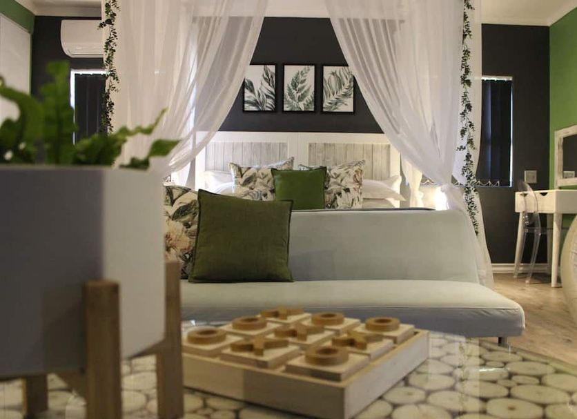 Club Cocomo in Hartbeespoort guest room with canopy bed, green accents, sofa, and patterned tile floor