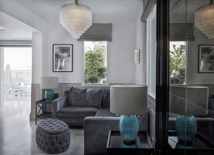 Mim Ibiza Meliá Collection in Ibiza, stylish lounge with gray sofa, tufted ottoman, and balcony view