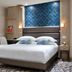 Serotel Suites Paris guest room with double bed, blue headboard accent wall and patterned carpet