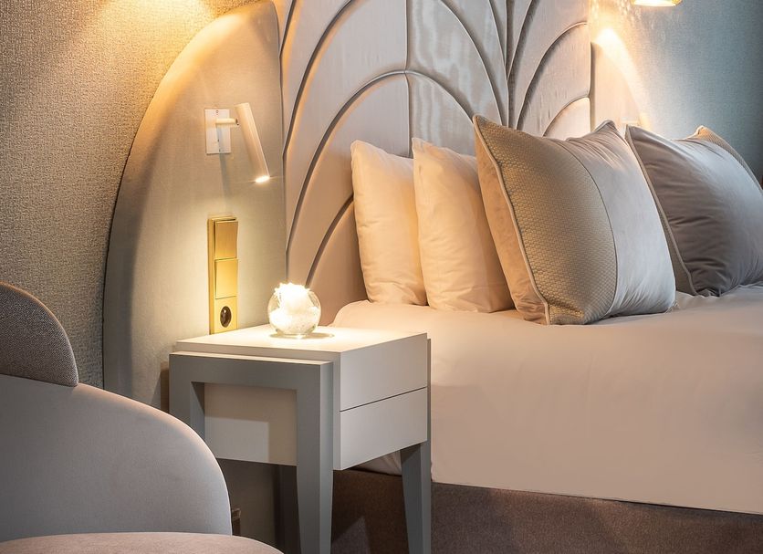 Hôtel le Derby Alma by Inwood Hotels room in Paris with plush bed, bedside table and wall sconces