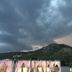 The Sarigerme Inn in Sarigerme with storm clouds over hills and lit outdoor cabanas