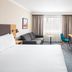 Holiday Inn London - Gatwick Airport By IHG room with bed, sofa, desk and wall-mounted TV in Gatwick