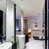 Sozo Hotel Nantes bathroom with glass shower, round tub, and purple-lit mirrored vanity