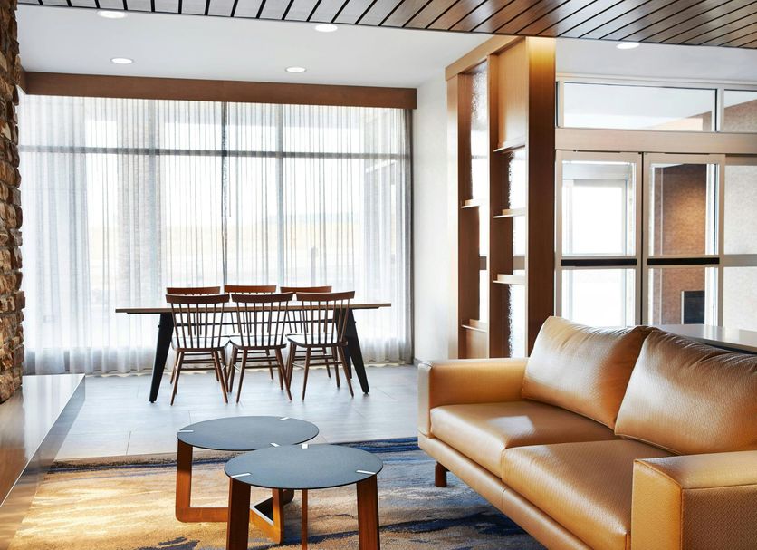 Fairfield Inn & Suites by Marriott Sheboygan lobby with leather sofa, side tables, dining area and stone wall