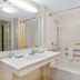 La Quinta Inn & Suites By Wyndham Dfw Airport South / Irving bathroom with tub, vanity and orange-striped shower curtain