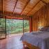 Cabañas La Pradera Monteverde cabin bedroom with wood walls and balcony overlooking lush greenery
