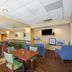 Hampton Inn Maysville lobby lounge with tables, chairs and wall-mounted TV in Maysville