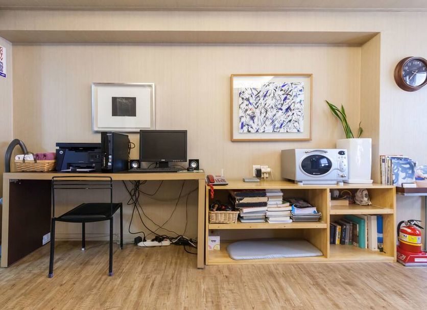 Yehadoye Guesthouse Seoul room with desk, chair, computer monitor, shelves of books, and microwave