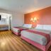 Motel 6-Fairfield, Ca - North guest room with two beds, orange accent wall, and wood-look floor