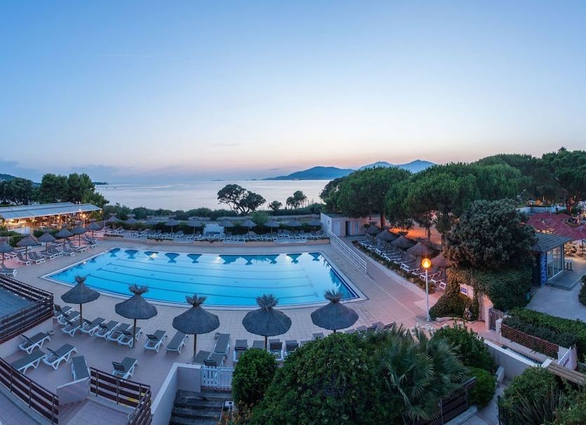 Hotel Club Marina Viva in Porticcio with outdoor pool, sun loungers, and sea view at dusk