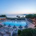 Hotel Club Marina Viva in Porticcio with outdoor pool, sun loungers, and sea view at dusk