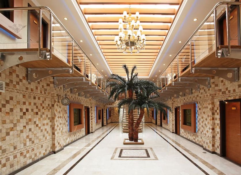 Arya Hotel Sakarya lobby hallway with chandelier, palm tree centerpiece and mosaic walls in Adapazarı