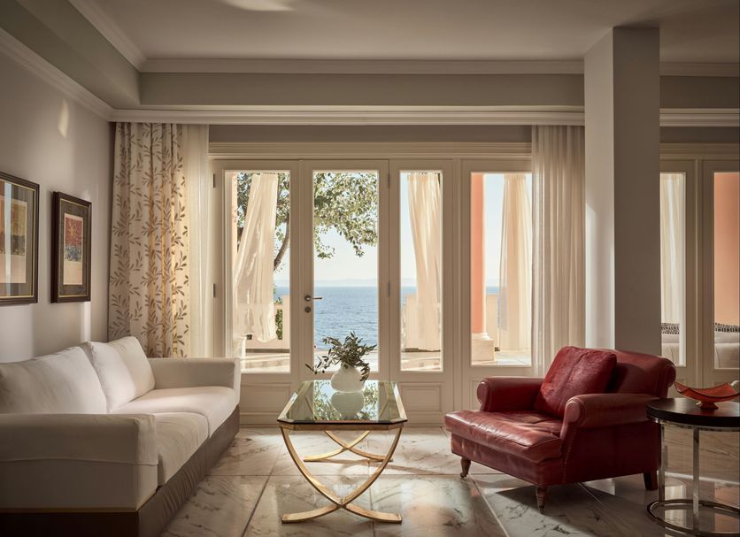 The Danai, Nikiti: elegant suite with sea view through glass doors and red armchair