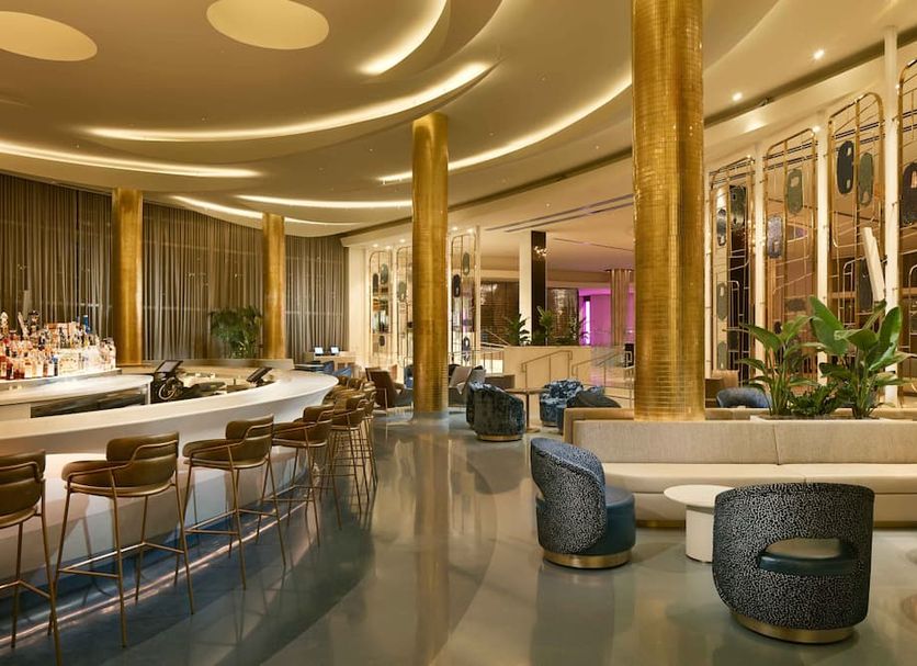 Fontainebleau Miami Beach lobby bar with gold columns, curved seating, and polished floors