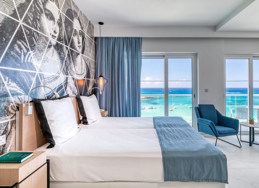 King Jason Protaras in Protaras bedroom with sea view, blue chairs and balcony doors