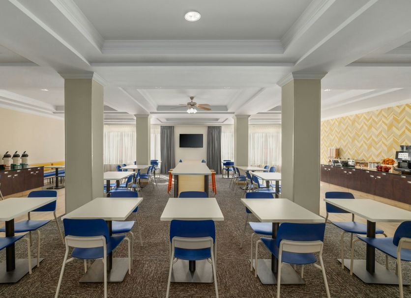 Breakfast room at City Express by Marriott Washington, DC Northeast with tables, blue chairs, and buffet stations.