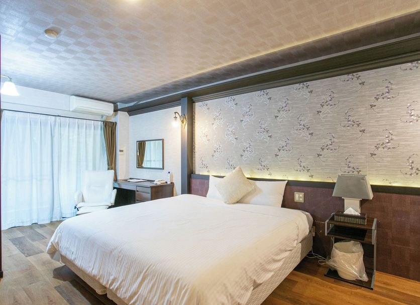 Yufuin Besso Shikisai Hotel in Yufu guest room with large bed, desk, and sliding curtains