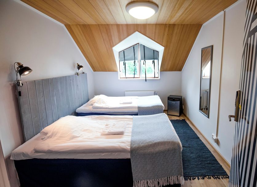 Hostel Villa Kemi in Kemi: cozy attic twin room with sloped wood ceiling, window, and simple beds