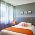 Cozy Hotel in Plouigneau guest room with bed, orange throw, bedside lamp and large window