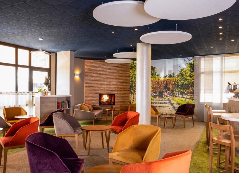 Hôtel Mercure Trouville-sur-Mer lounge with colorful chairs, fireplace and large windows in Trouville-sur-Mer