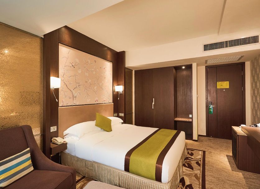 Zhehai Hotel Ningbo guest room with a bed, wall art, seating area and wood-paneled entrance in Ningbo