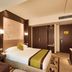 Zhehai Hotel Ningbo guest room with a bed, wall art, seating area and wood-paneled entrance in Ningbo