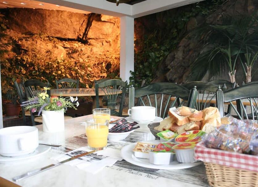Contact Hotel Le Moulin Neuf Chantonnay breakfast table with pastries, orange juice and a garden backdrop