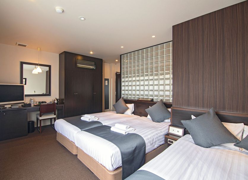 Wonz Hotel Osaka room with two beds, desk, TV and glass-block wall