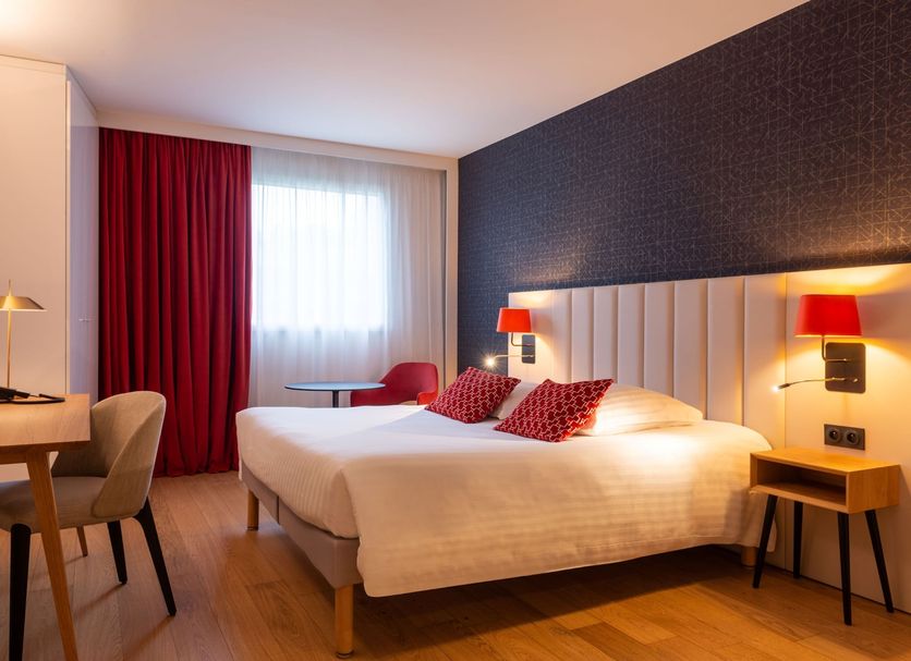 L'Amirauté Brest hotel room in Brest with a double bed, desk, red curtains, and modern bedside lamps