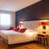 L'Amirauté Brest hotel room in Brest with a double bed, desk, red curtains, and modern bedside lamps
