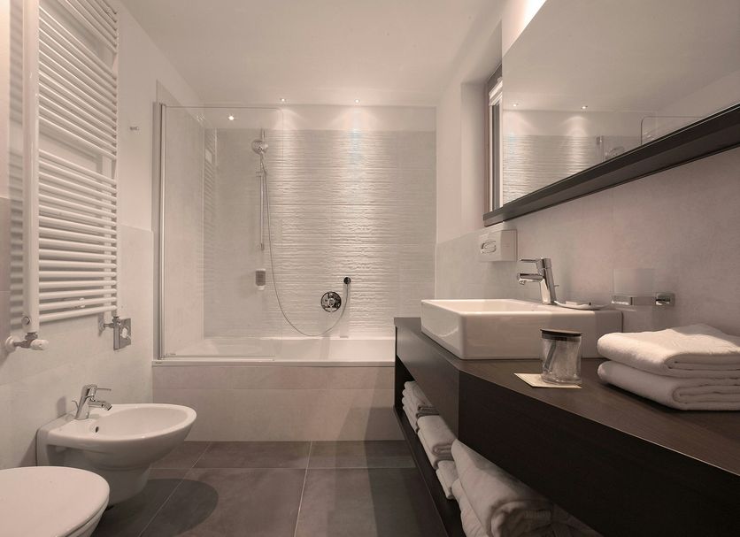 Soleil Alpine Lifestyle Hotel bathroom in Badia/Abtei with bathtub, bidet, sink, and large mirror