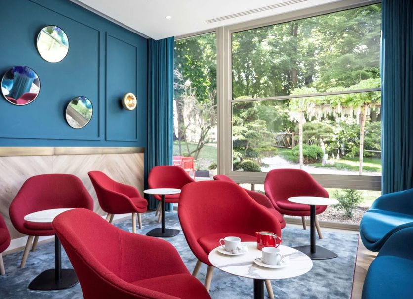 Golden Tulip Aix Les Bains lounge with red chairs and large garden-view windows in Aix-les-Bains