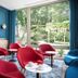 Golden Tulip Aix Les Bains lounge with red chairs and large garden-view windows in Aix-les-Bains