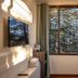 Hotel Woodrina in Shimla room with wall-mounted TV, window view of trees, and folded towels