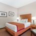 Baymont by Wyndham Savannah/Garden City guest room with king bed, bedside lamps, and patterned armchair in Savannah
