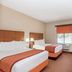 Baymont by Wyndham Savannah/Garden City hotel room with two beds, desk, and wall-mounted TV in Savannah