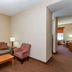 Baymont by Wyndham Savannah/Garden City living area with sofa, chair, coffee table and hallway to bedroom
