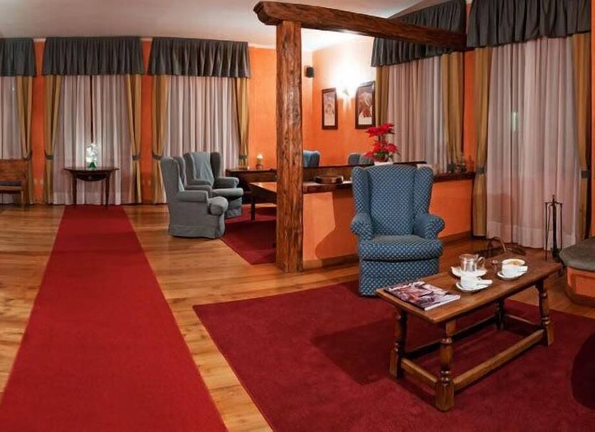 Hotel Crampon in Courmayeur lounge with red carpet, armchairs, coffee table and fireplace