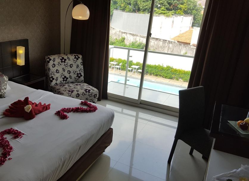 Sisingamangaraja Guest House Semarang room with king bed, balcony view and floral towel decor