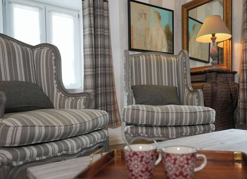 Auberge De La Poulcière in Gérardmer room with striped wingback chairs, lamp, and window